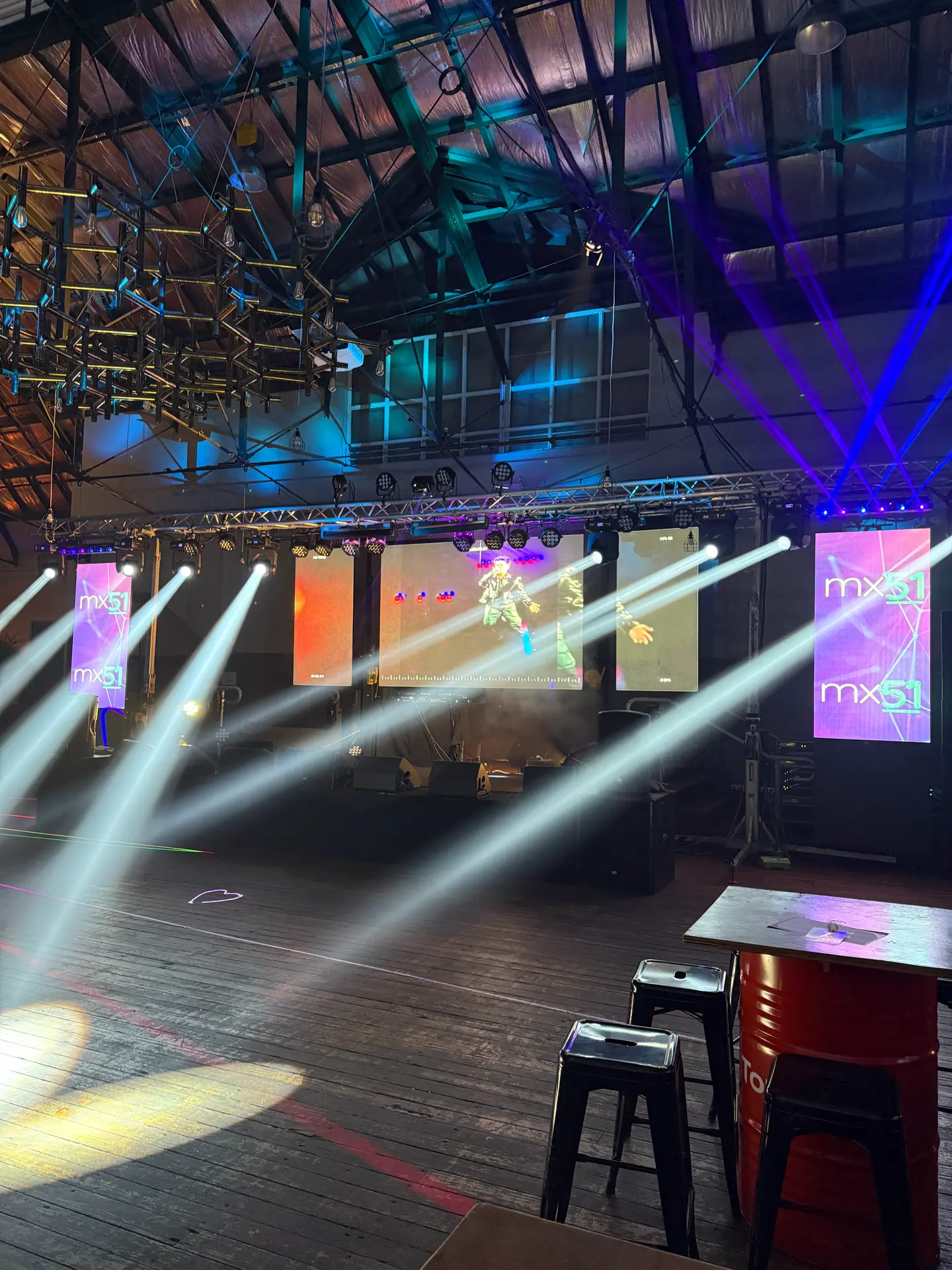 Multi-screen LED rig with truss and moving lights at an indoor music festival
