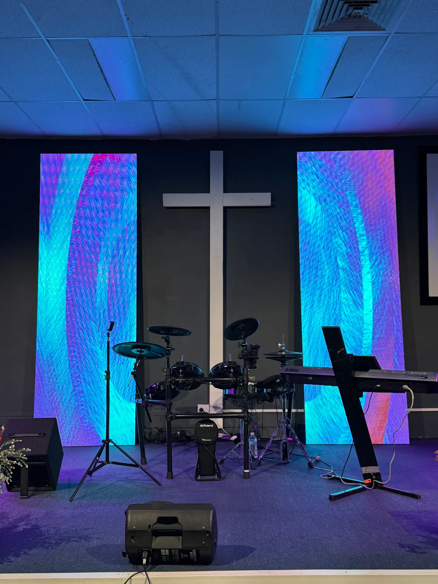 Two tall LED columns showing colourful motion graphics either side of a cross on a church stage