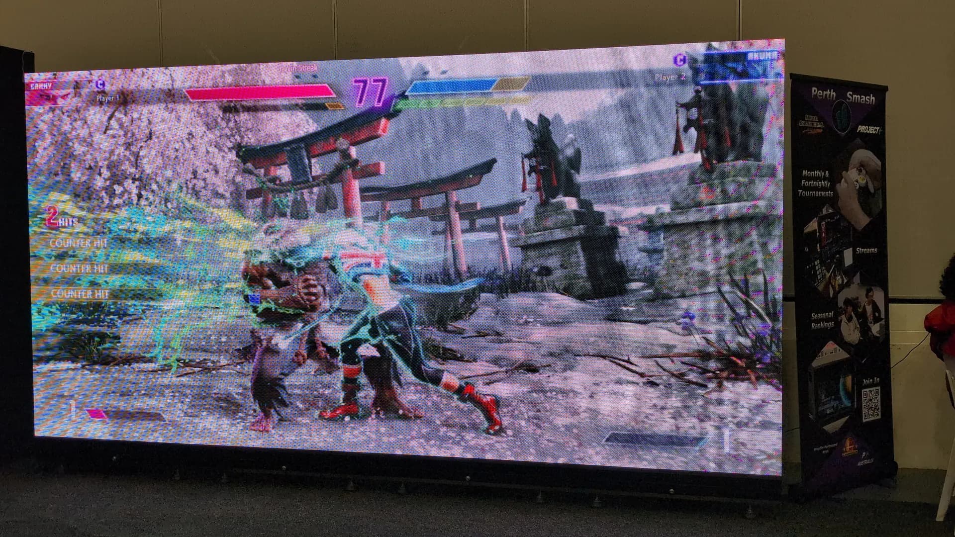 Fighting game tournament shown on a large LED screen at a gaming expo