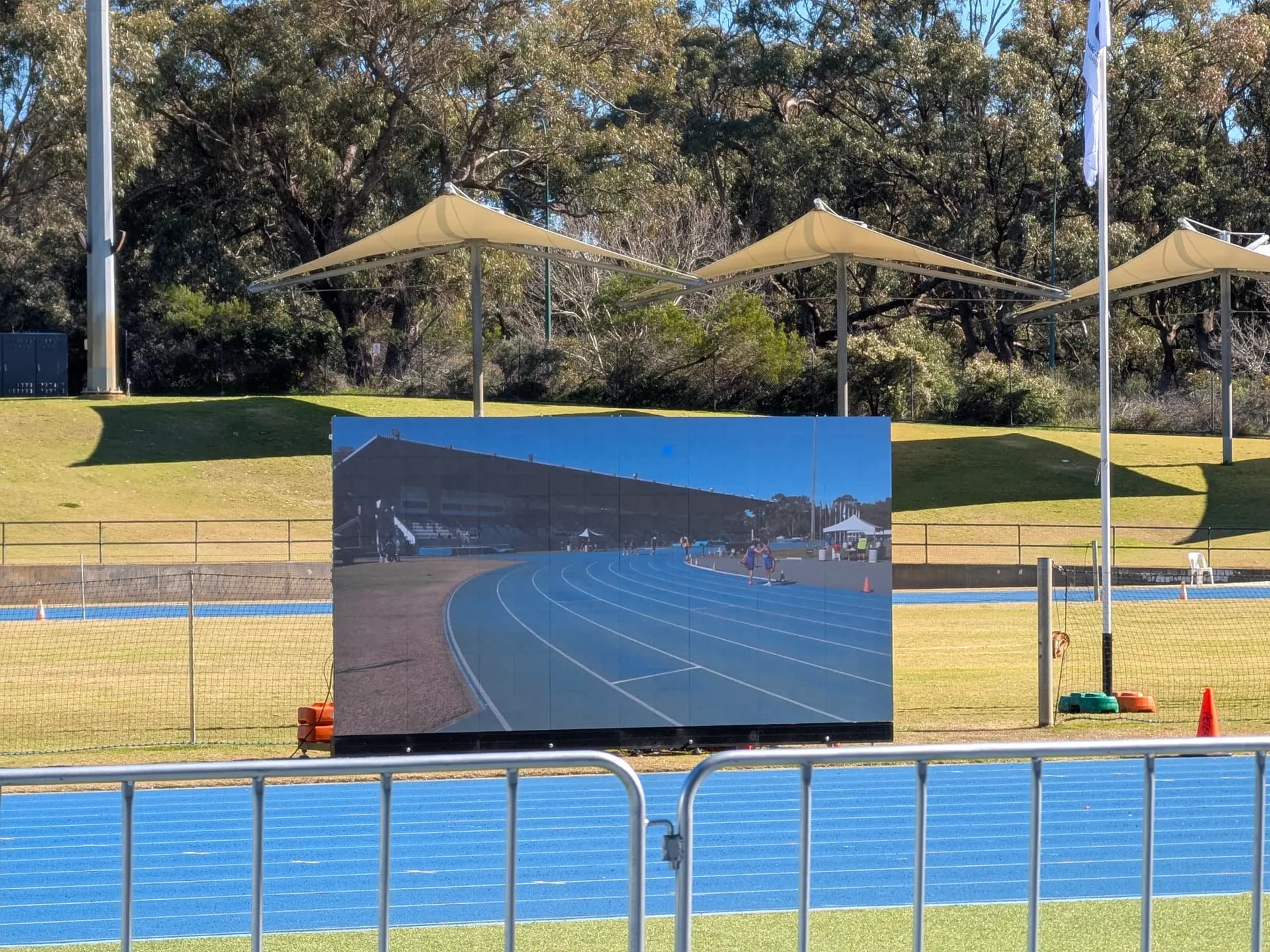 Outdoor LED screen showing a live track feed in direct sunlight