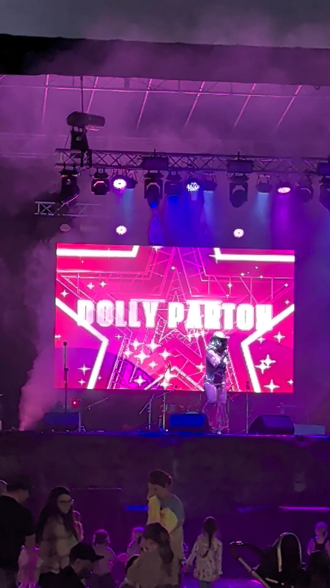 Elevated LED screen above a festival stage under purple show lighting